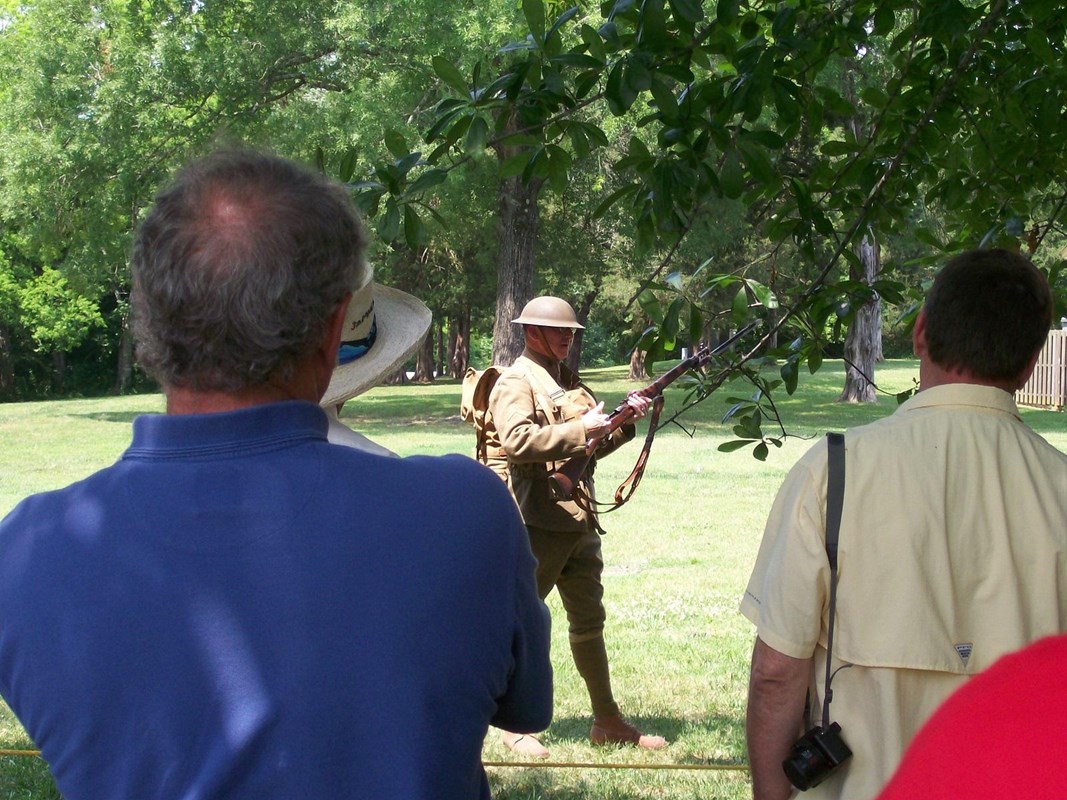 Living historian in green uniform and helmet portraying a World War One soldier.