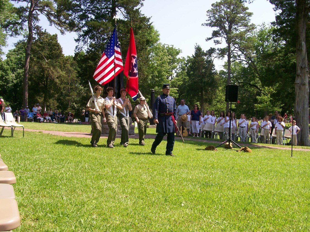 Man in blue uniform leads a boy scout honor guard carrying the US and Tennessee state flags