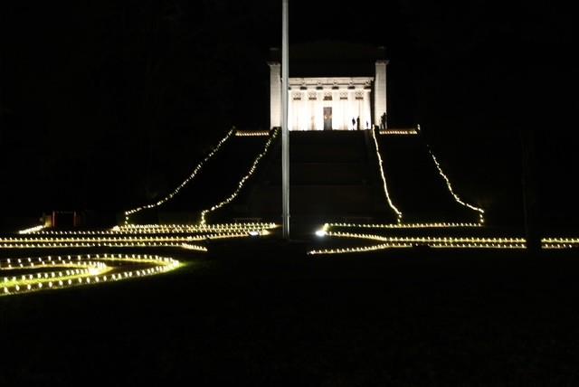 A color photo showing the white columned Memorial Building at night surrounded by Christmas lights