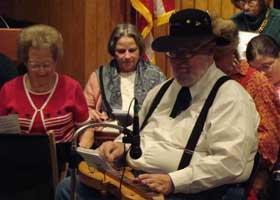 Several people sit down while playing dulcimers.