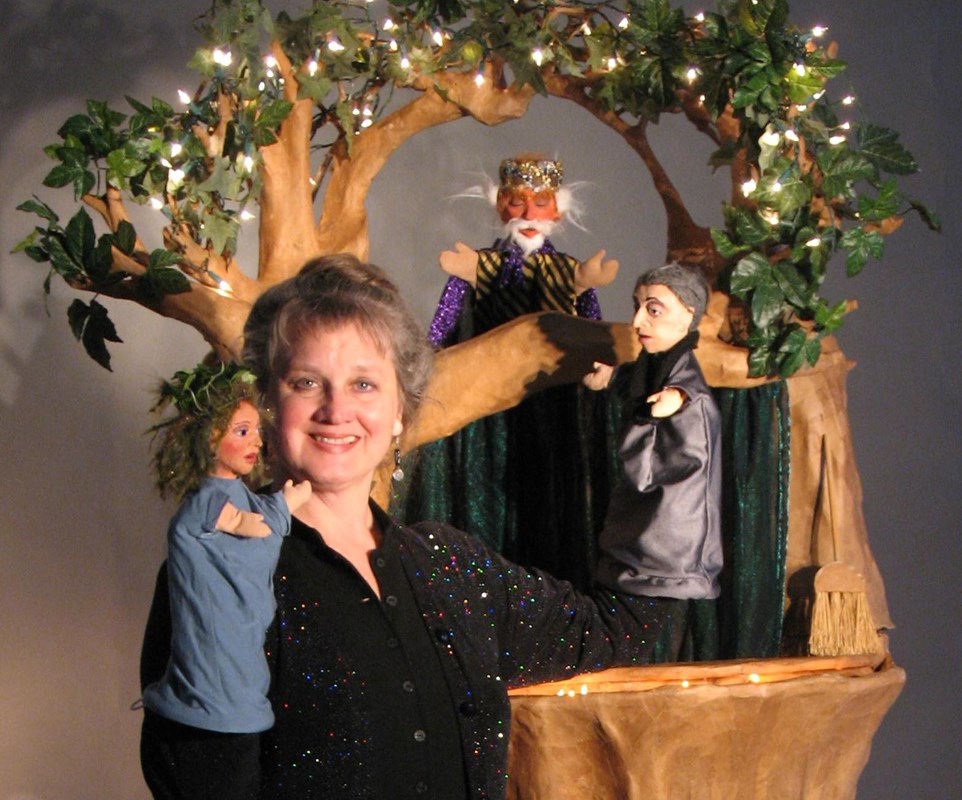 Woman puppeteer with three puppets near tree
