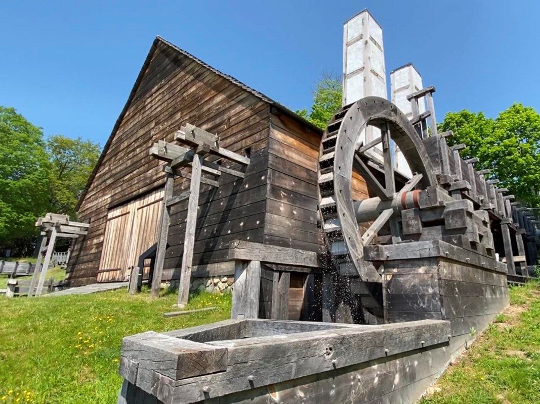 A large wooden waterwheel next to a wooden building.