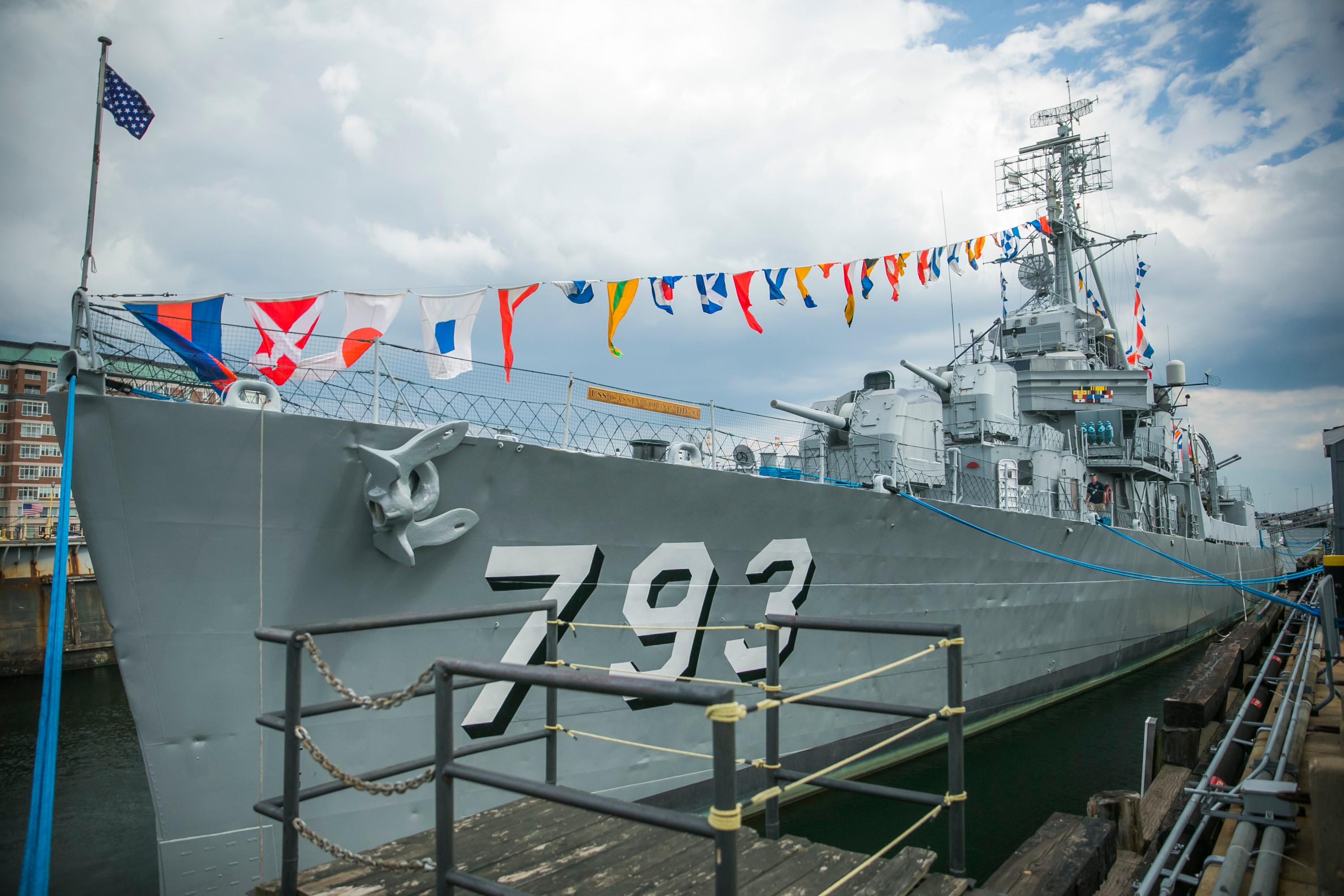 View of Cassin Young docked at a pier with nautical flags displayed.