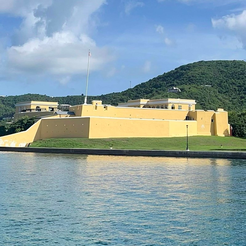 Yellow fort with water in the foreground and mountain in the background