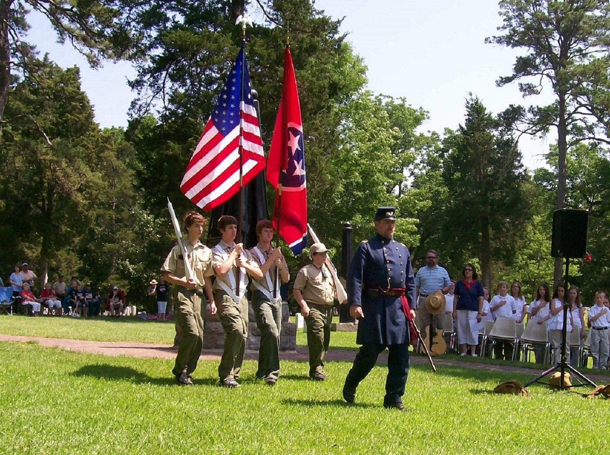 Living historian in blue uniform leads a boy scout honor guard.