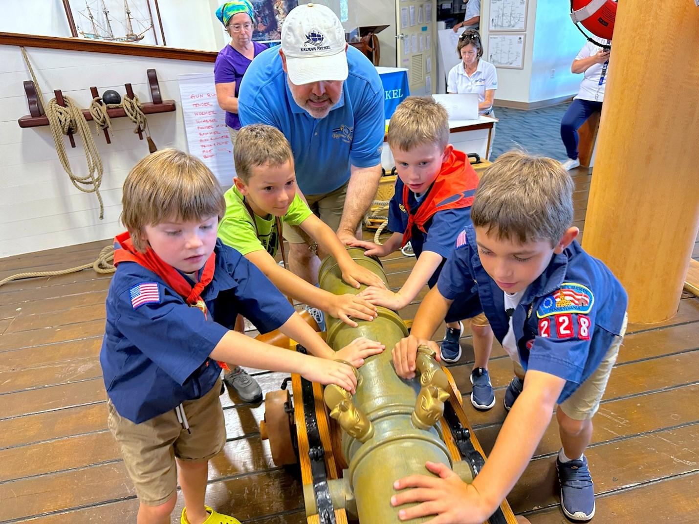 Boy scouts push a pretend canon.
