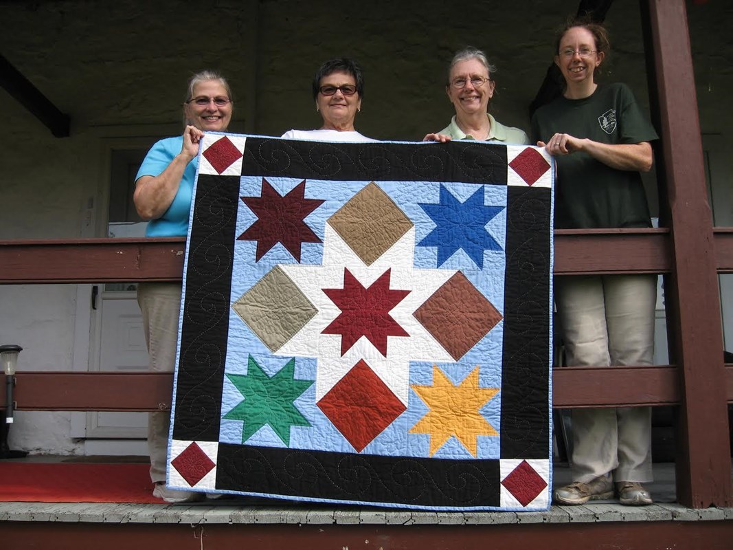 The Hopewell Quilters holding their hand sewed quilt