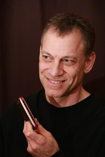 man holding a harmonica wearing a black shirt