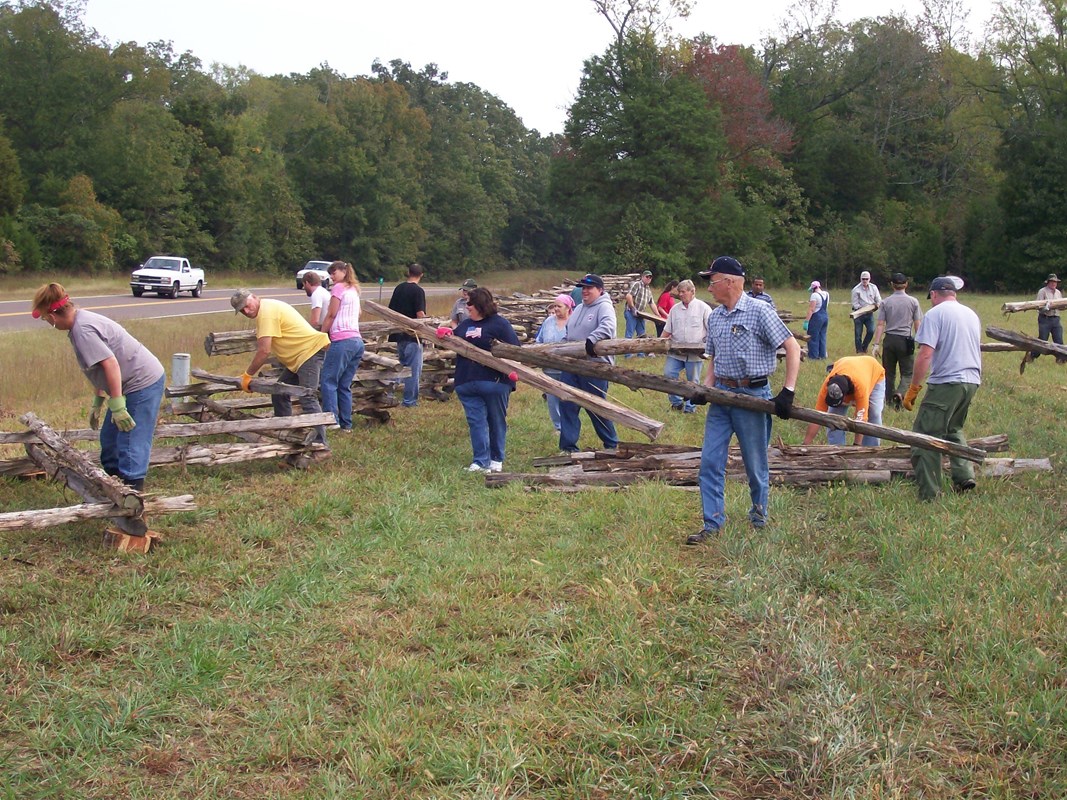 Volunteers building a split rail fence.