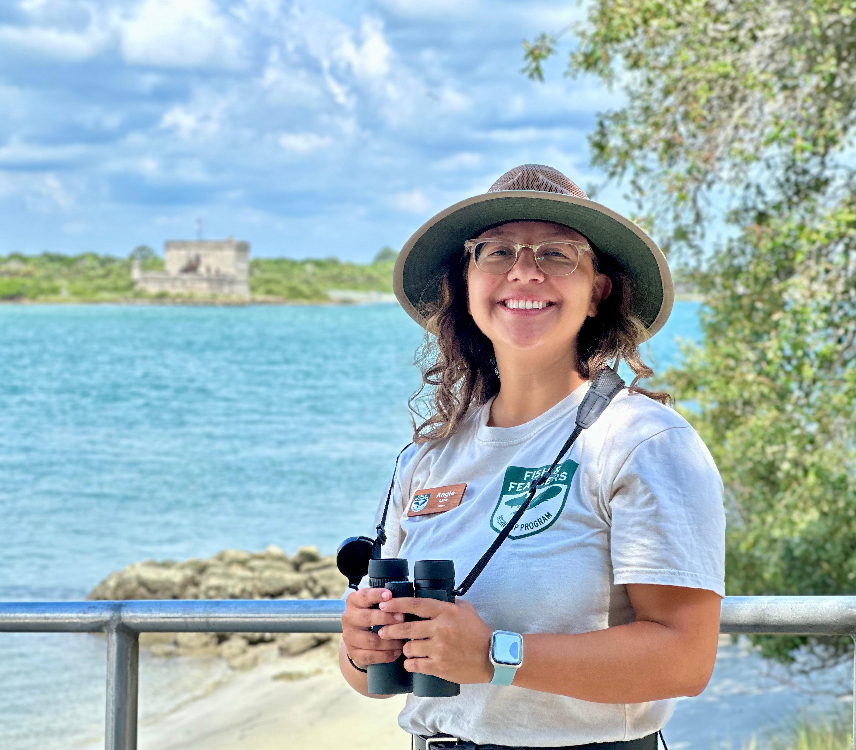 Woman smiling with river and fort in background.