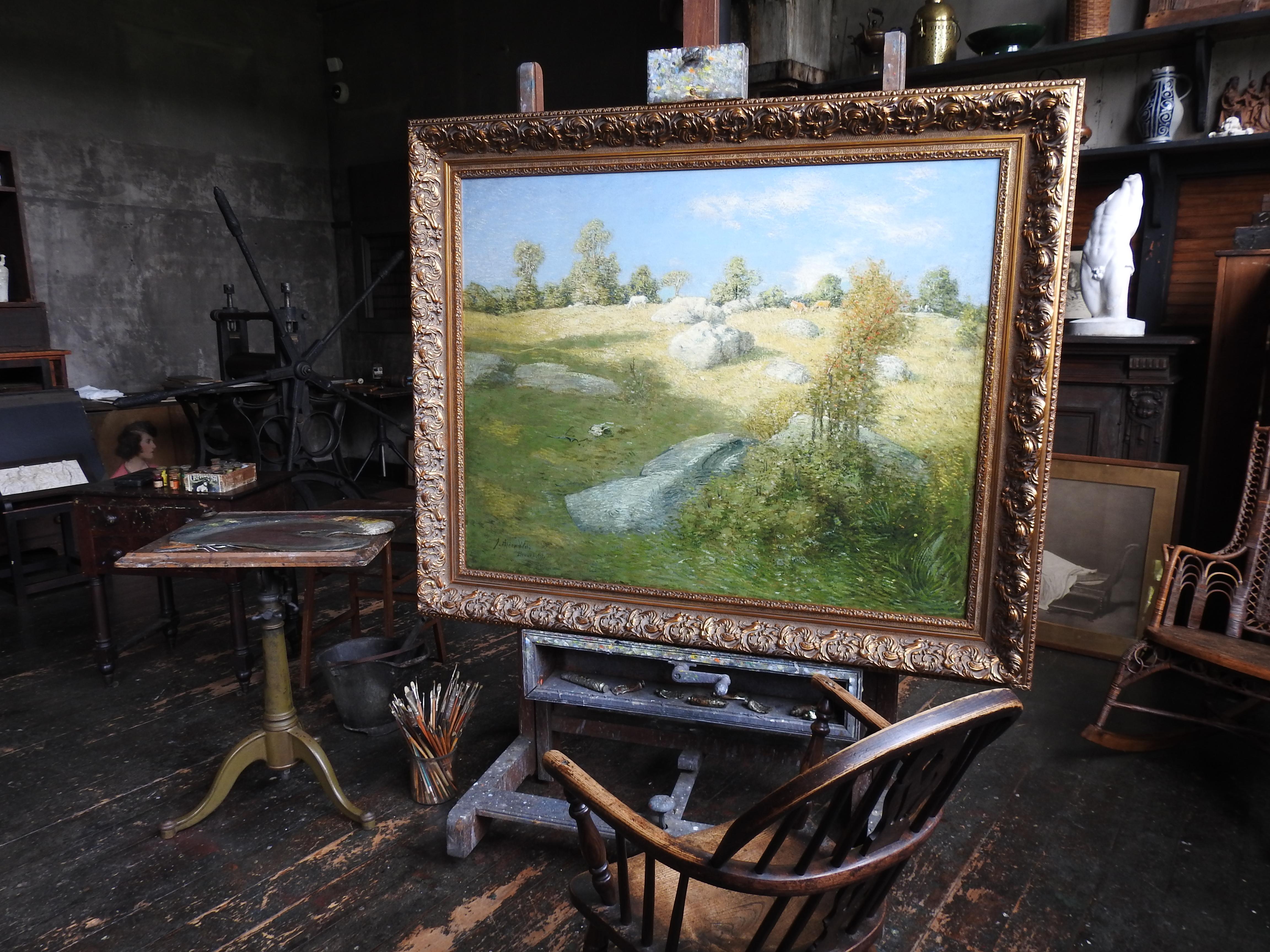 A work bench in a studio with painting tools and art on it.