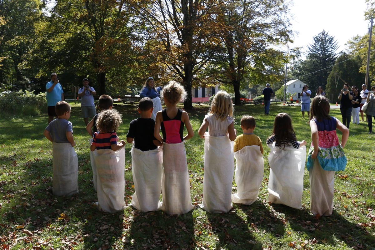 Children stand in a line wearing potato sacks preparing to race.
