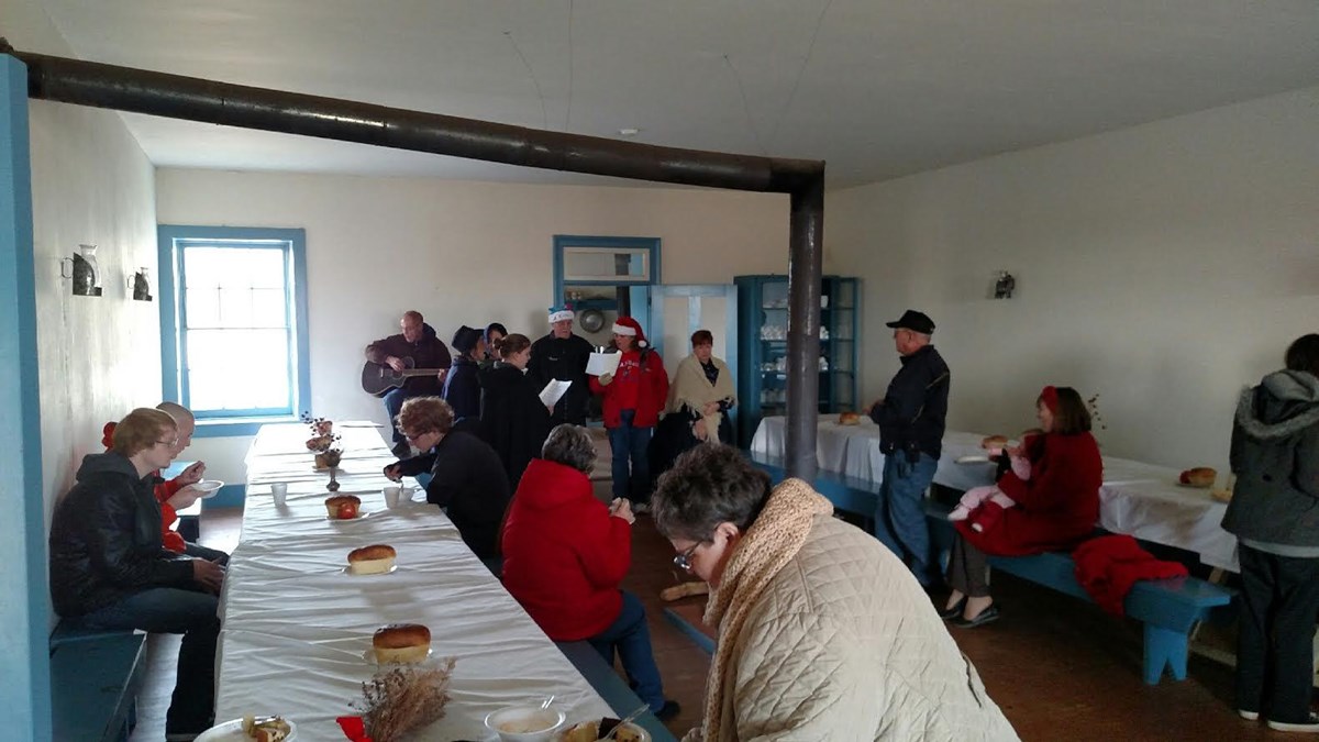 Visitors enjoying food and Christmas carols in the Barracks mess hall.