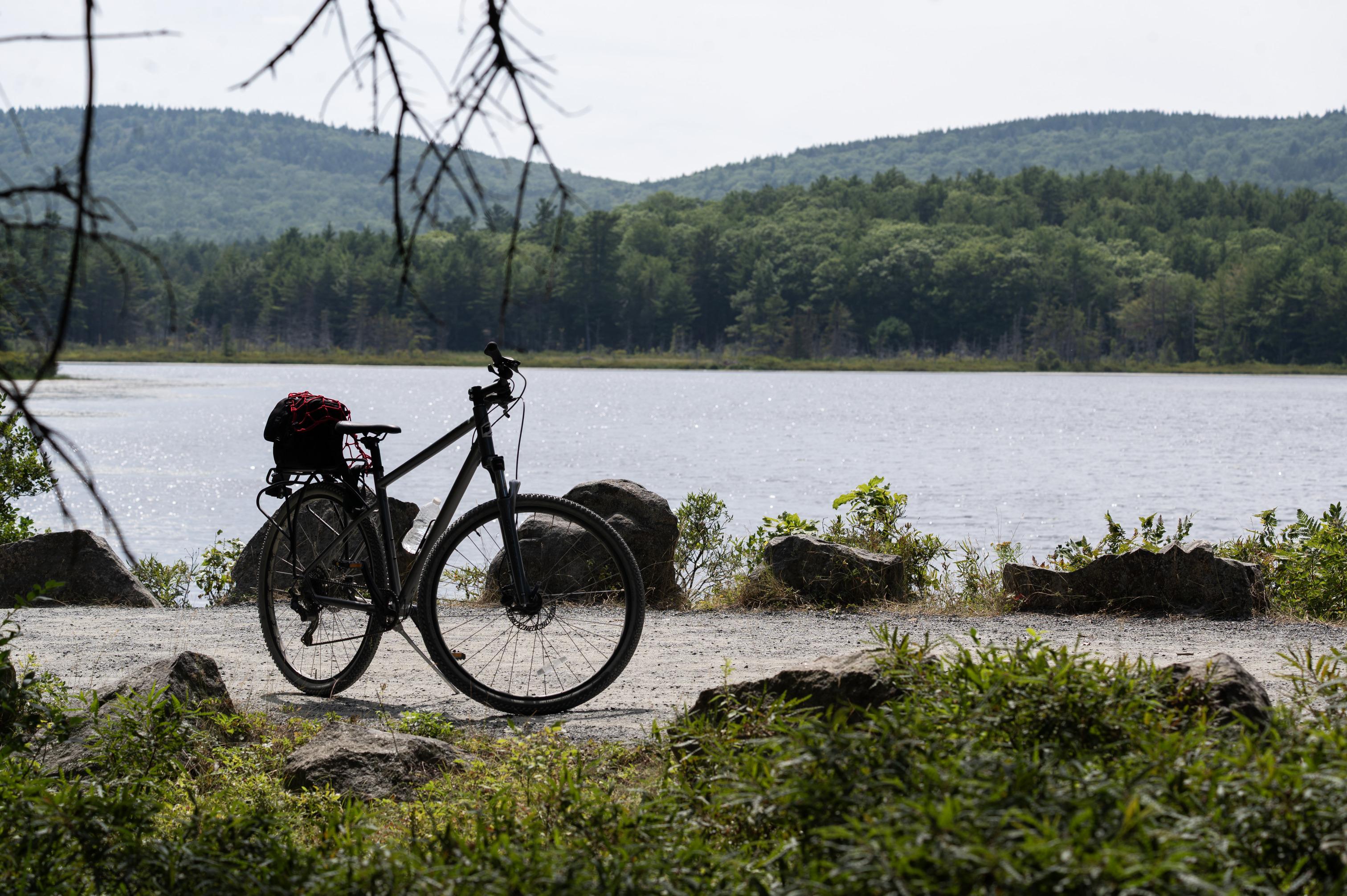 A bike stopped on the historic gravel carriage road overlooking a pond.