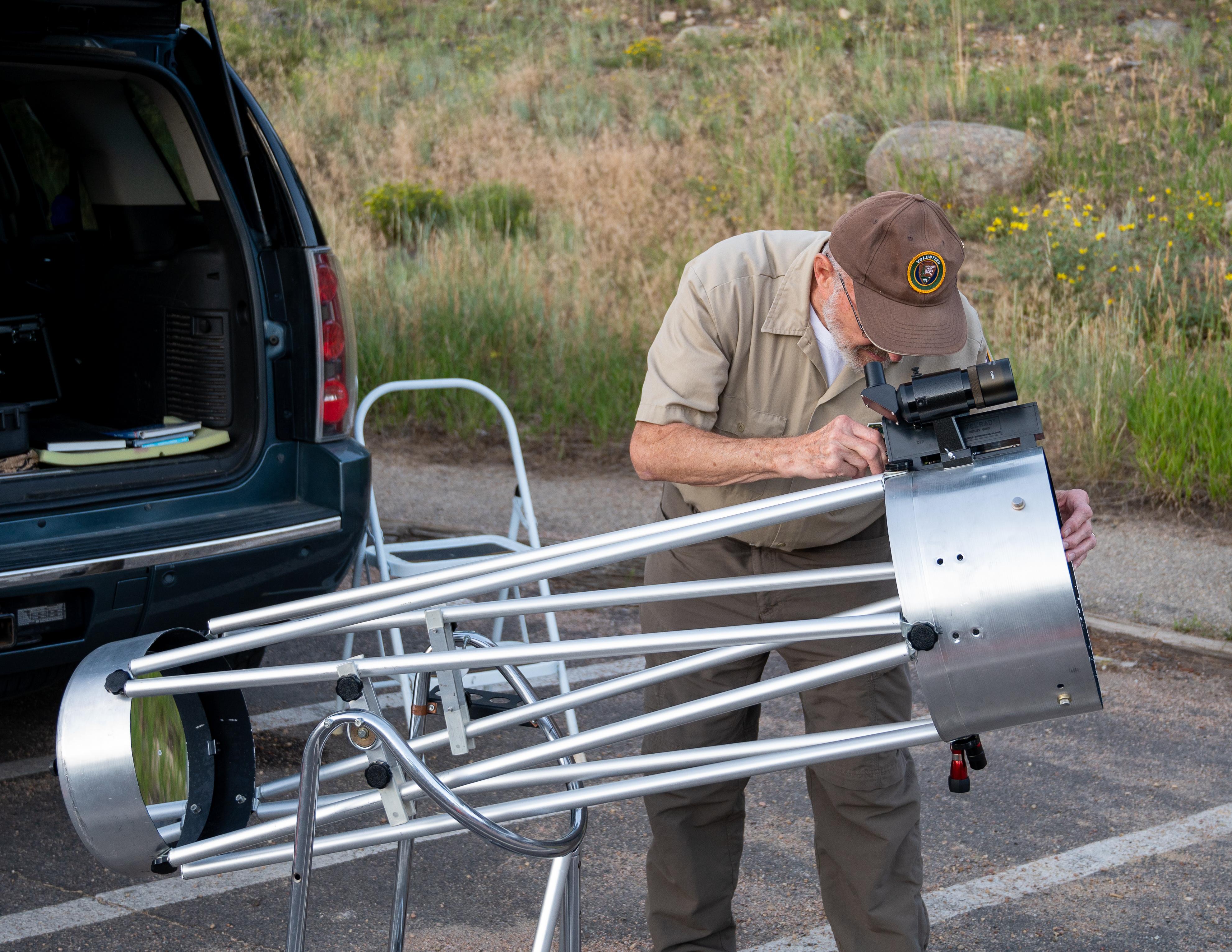 An NPS volunteer is looking up at the sky using a telescope
