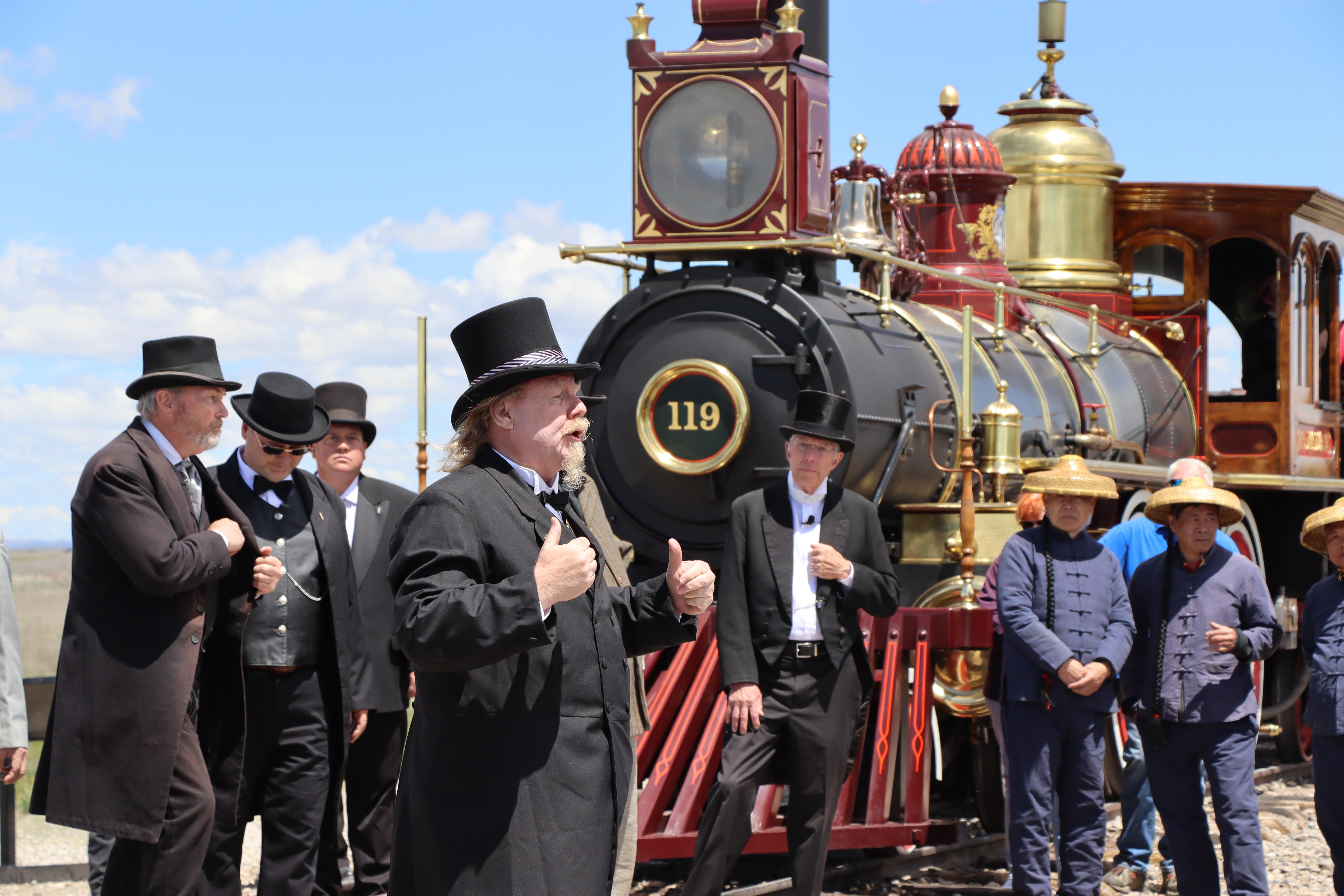 Living history actor in a Victorian age suit standing Infront of No.119 a historic locomotiv replica