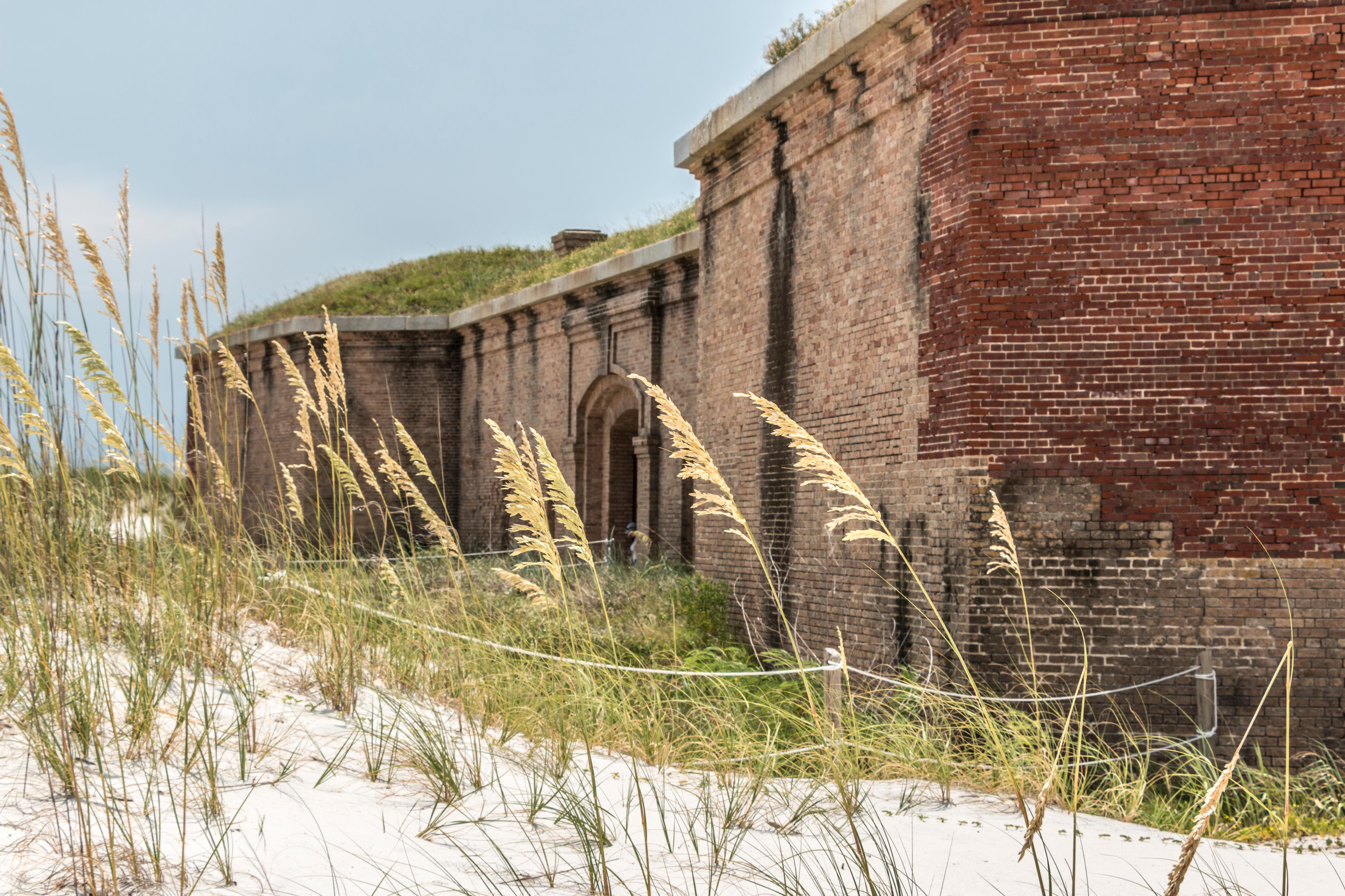 Sea oats grow in the foreground, a massive brick fort stands in the background.