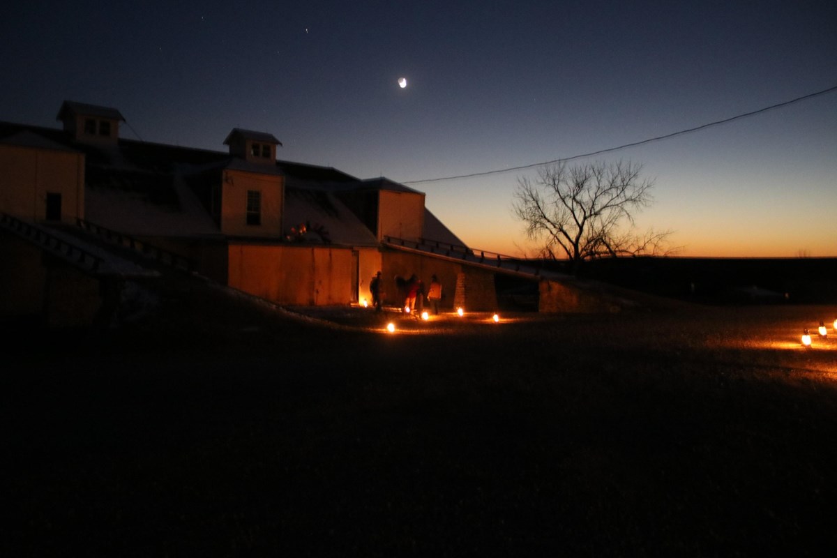 Historic barn being lit by moonlight and kerosene lanterns light the path along the Candlelight Tour