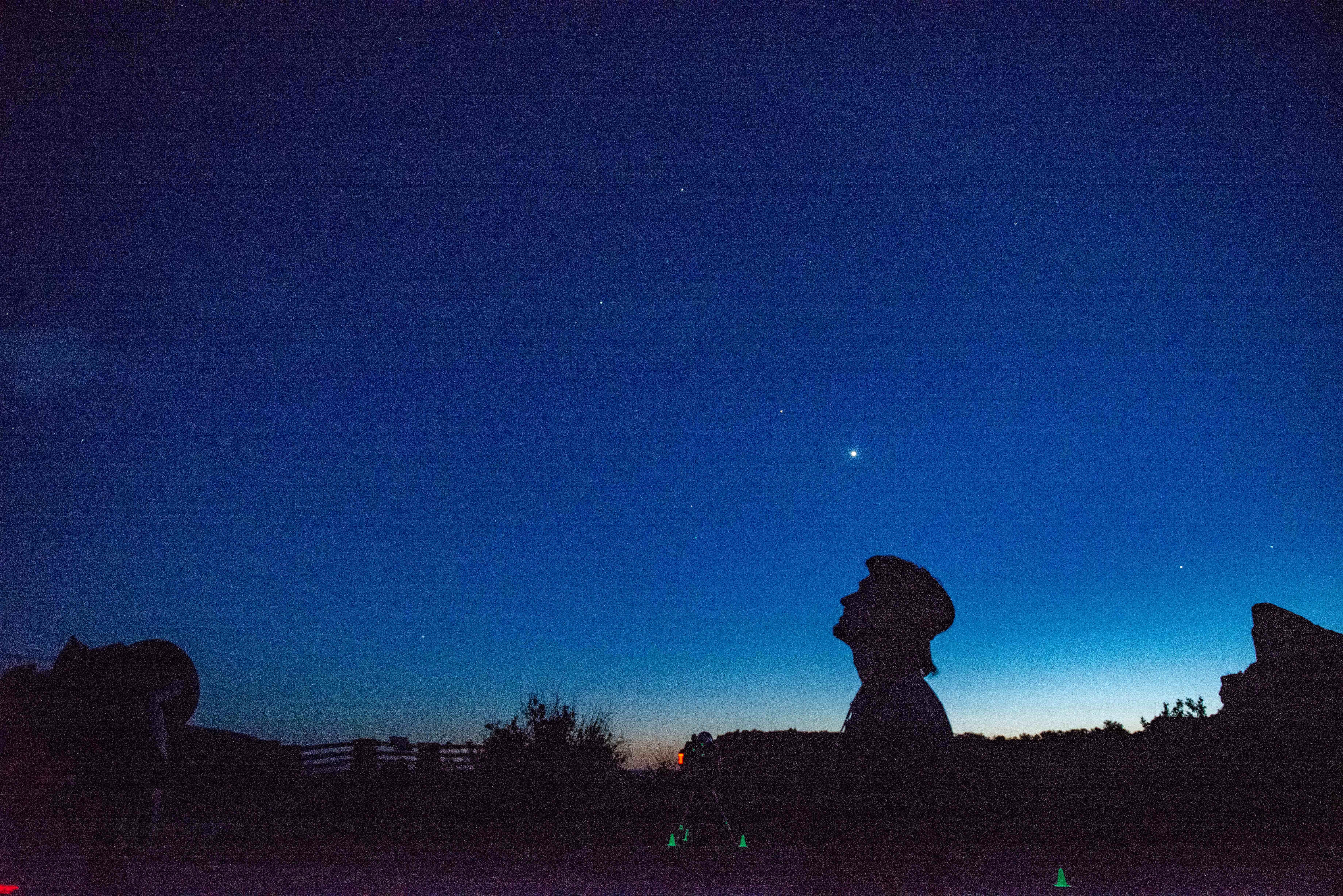 person's silhouette looking up at a starry night sky