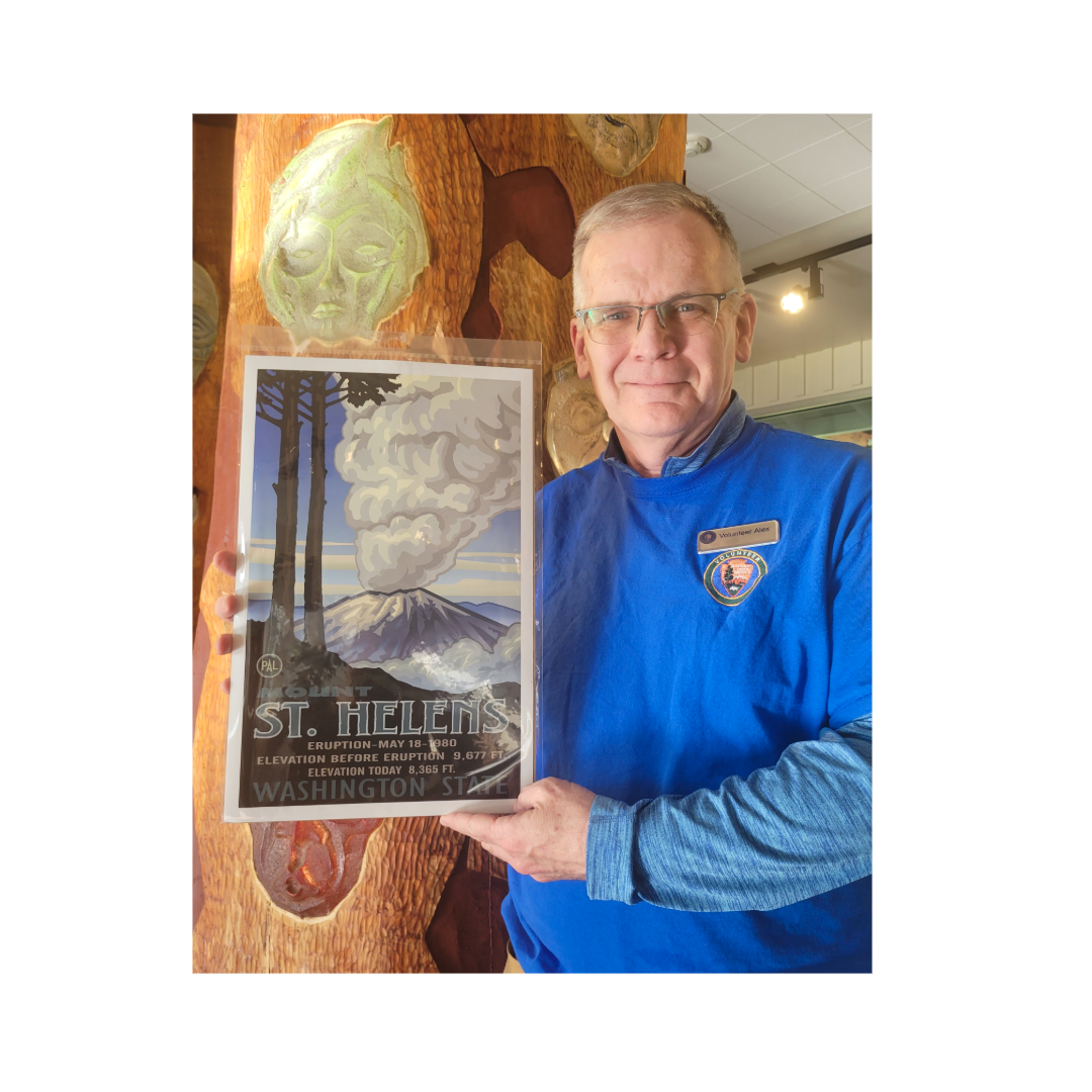 A volunteer in a blue shirt holding an illustration of the eruption of Mt. St. Helens