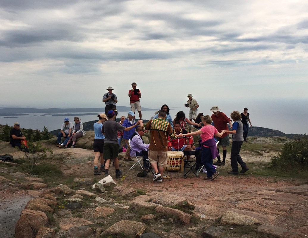 Dancers circle drummers on a mountain summit.