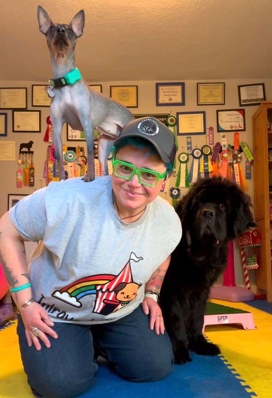 Author and Dog trainer kneeling with a small dog standing on her back and larger dog on her right