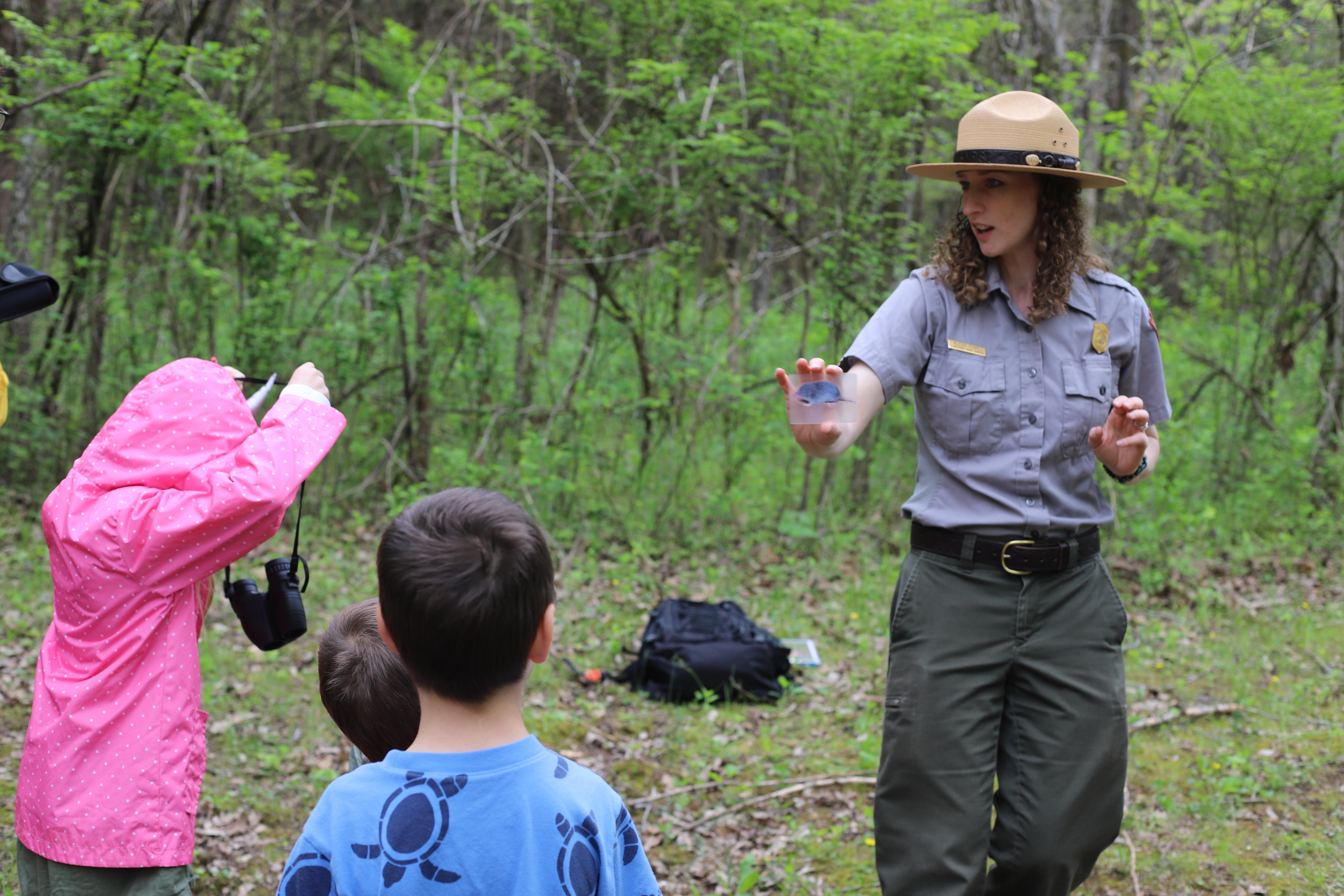 A ranger shows a laminated animal photo to 3 children