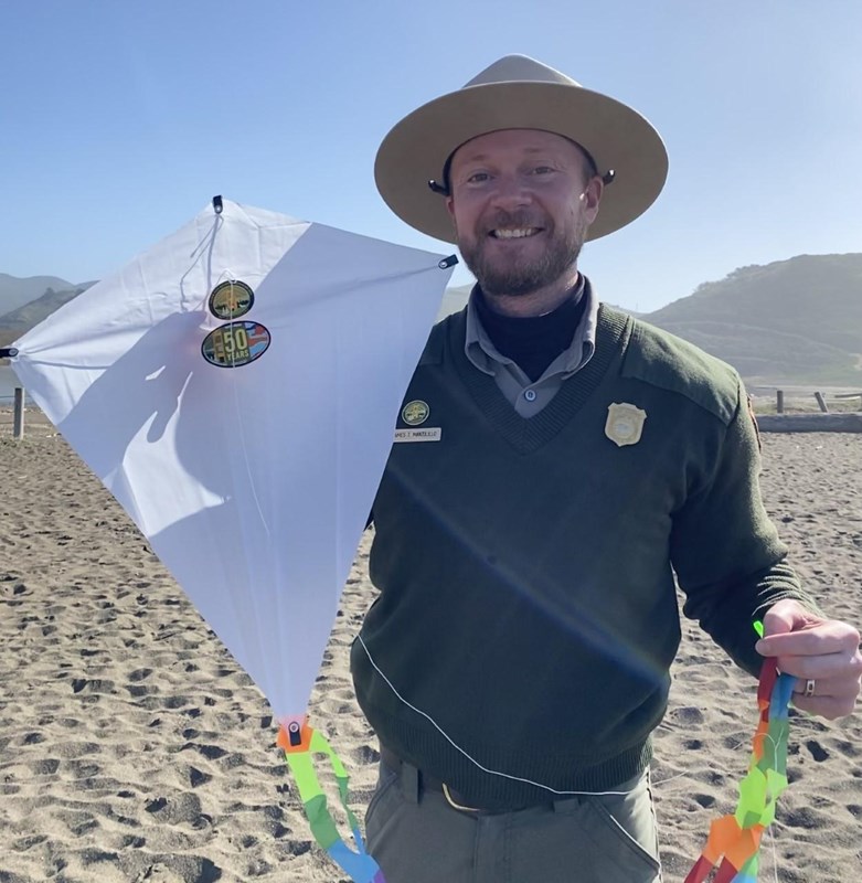 NPS Park Ranger holds a kite while standing on Rodeo Beach
