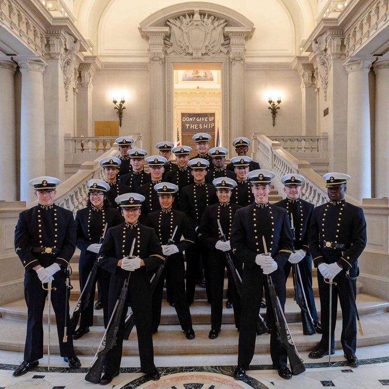 Color photo showing navy cadets with rifles standing in formation on a stair case.