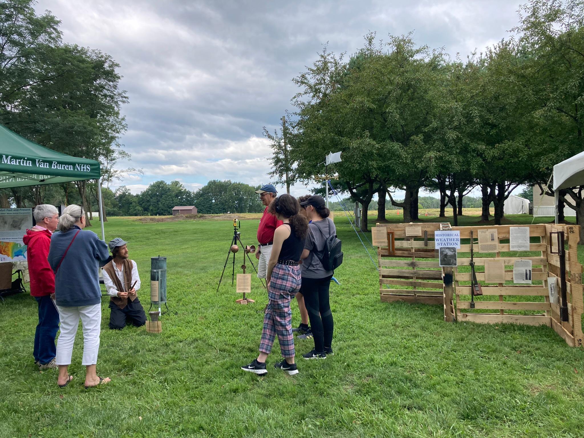 A costumed interpreter shows visitors vintage instruments at the Historical Weather Station display.