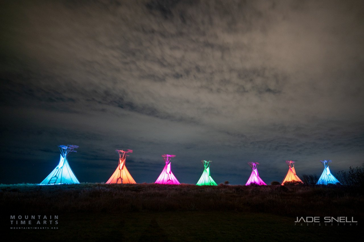 a row of illuminated and colorful teepees at night