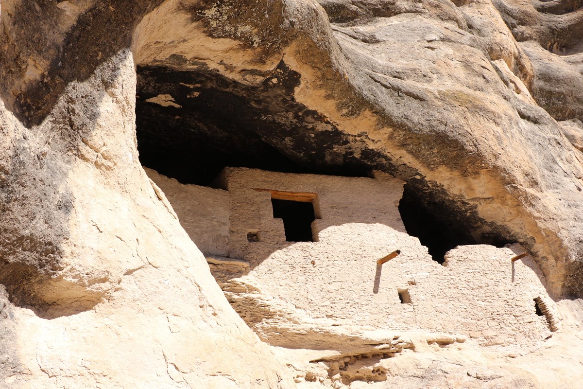 stone and mud walls in a cave with a T shaped door