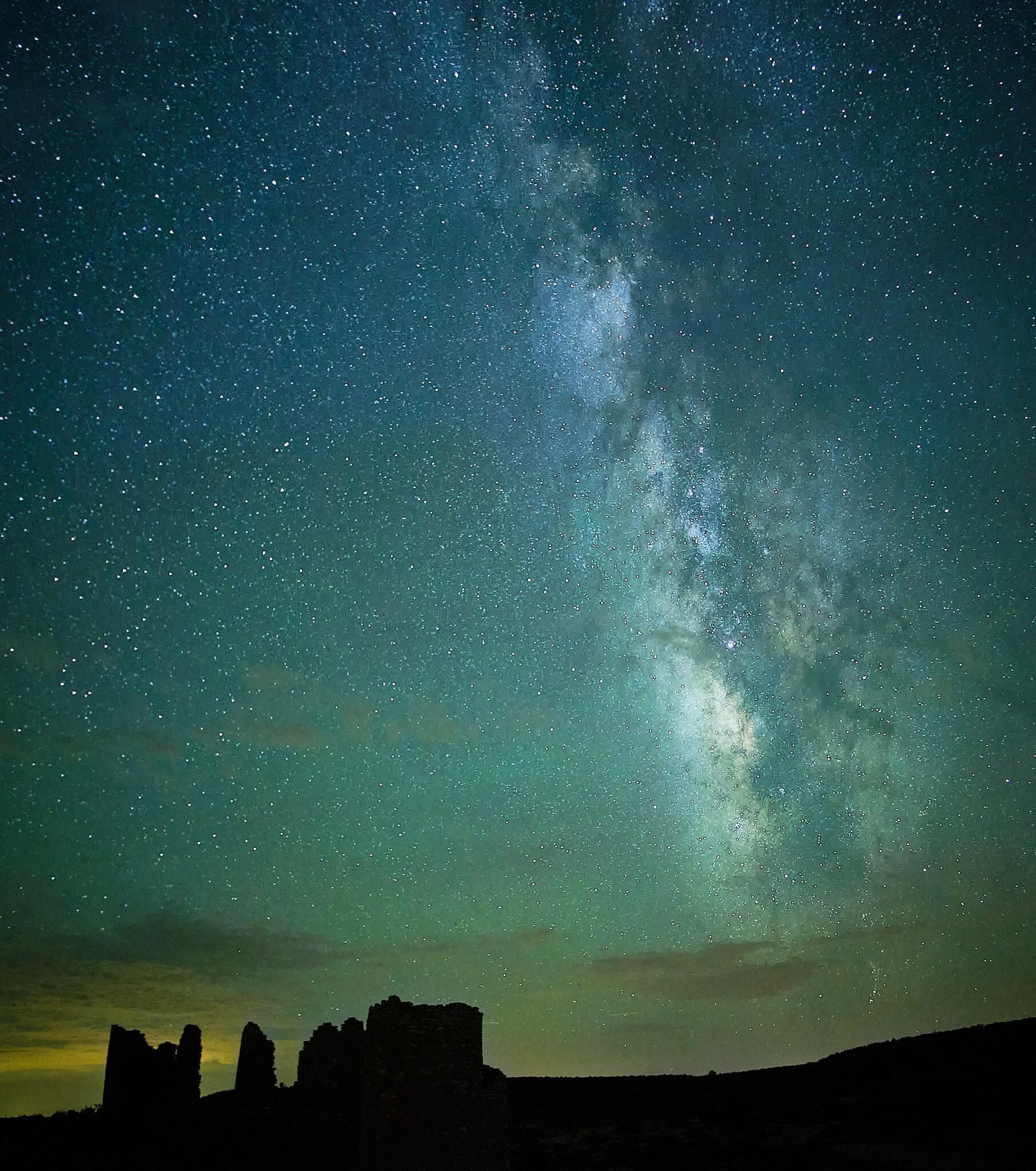 The milky way over a silhouette of structures.