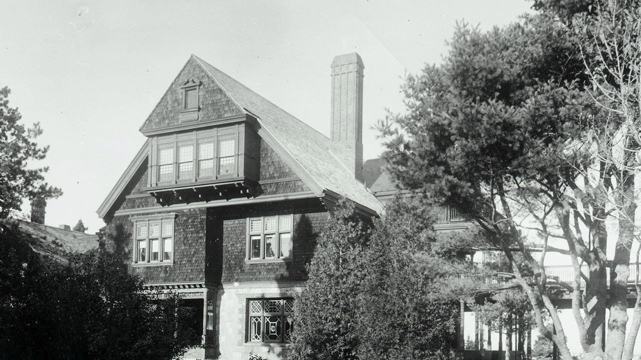 A black and white photo of a three story cottage.