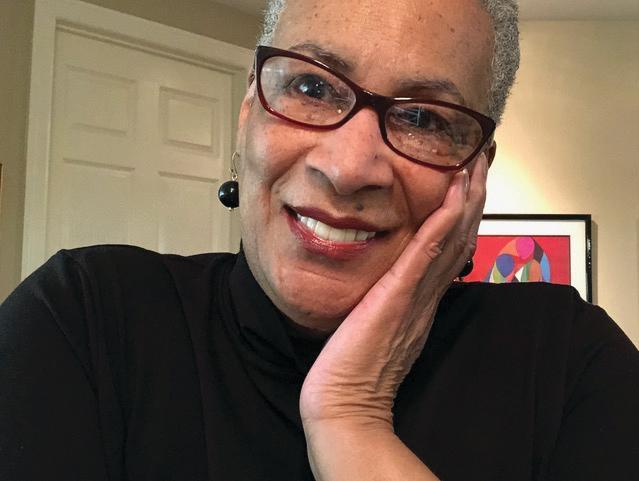 portrait of an African American woman with glasses in a black shirt leaning her head on her hand