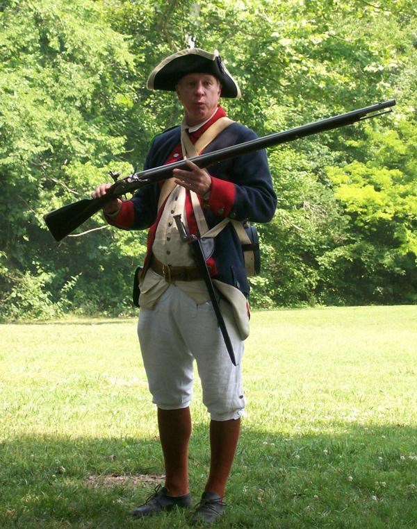 Living historian in Revolutionary War uniform holding a musket.