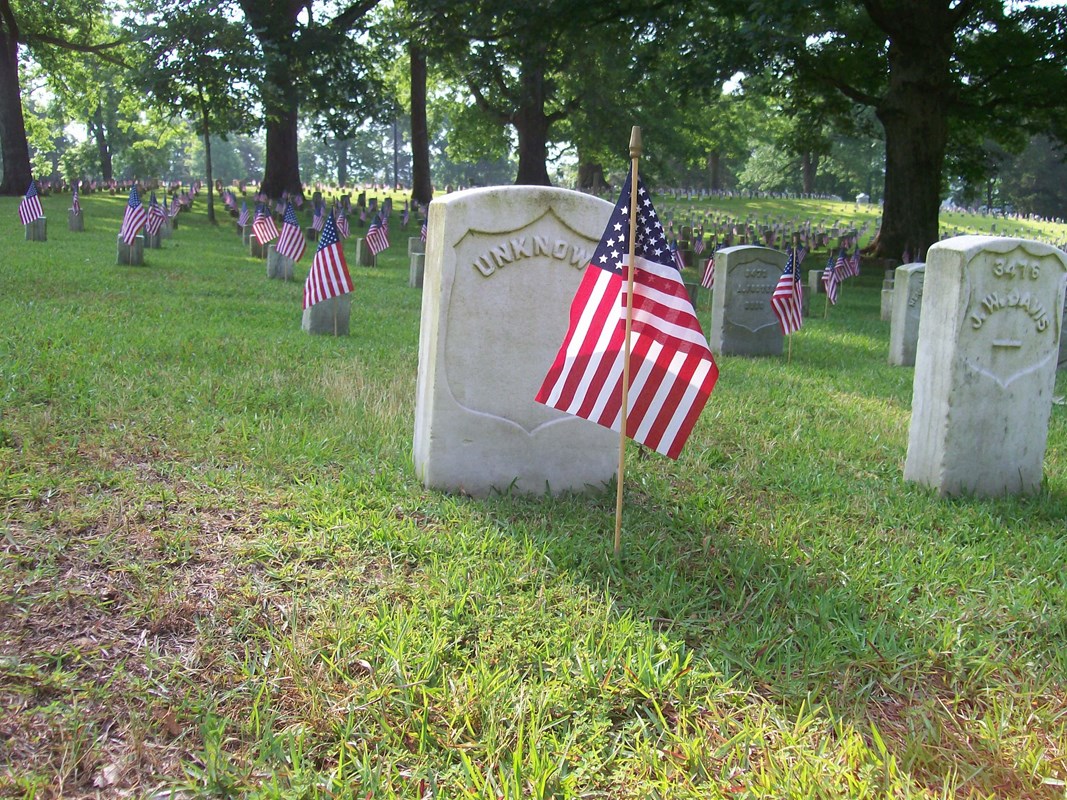 Unknown soldier's headstone with an American flag in front of it.