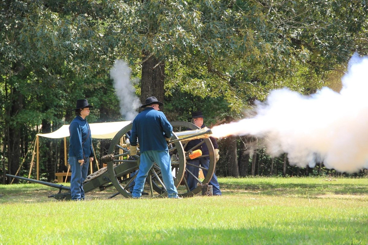 Living historians in Union uniforms fire a cannon.