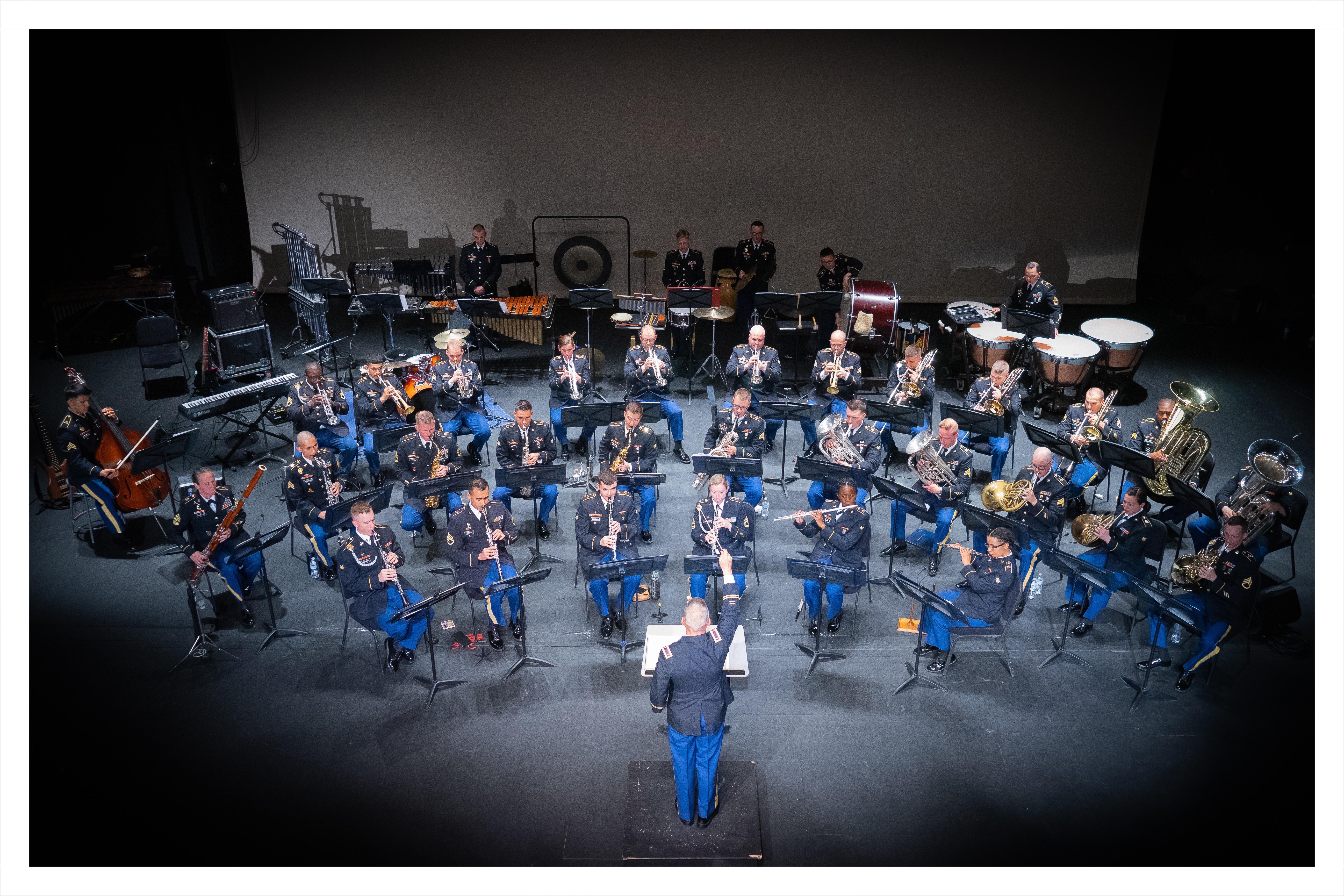42 uniformed military personnel in concert band half circle.