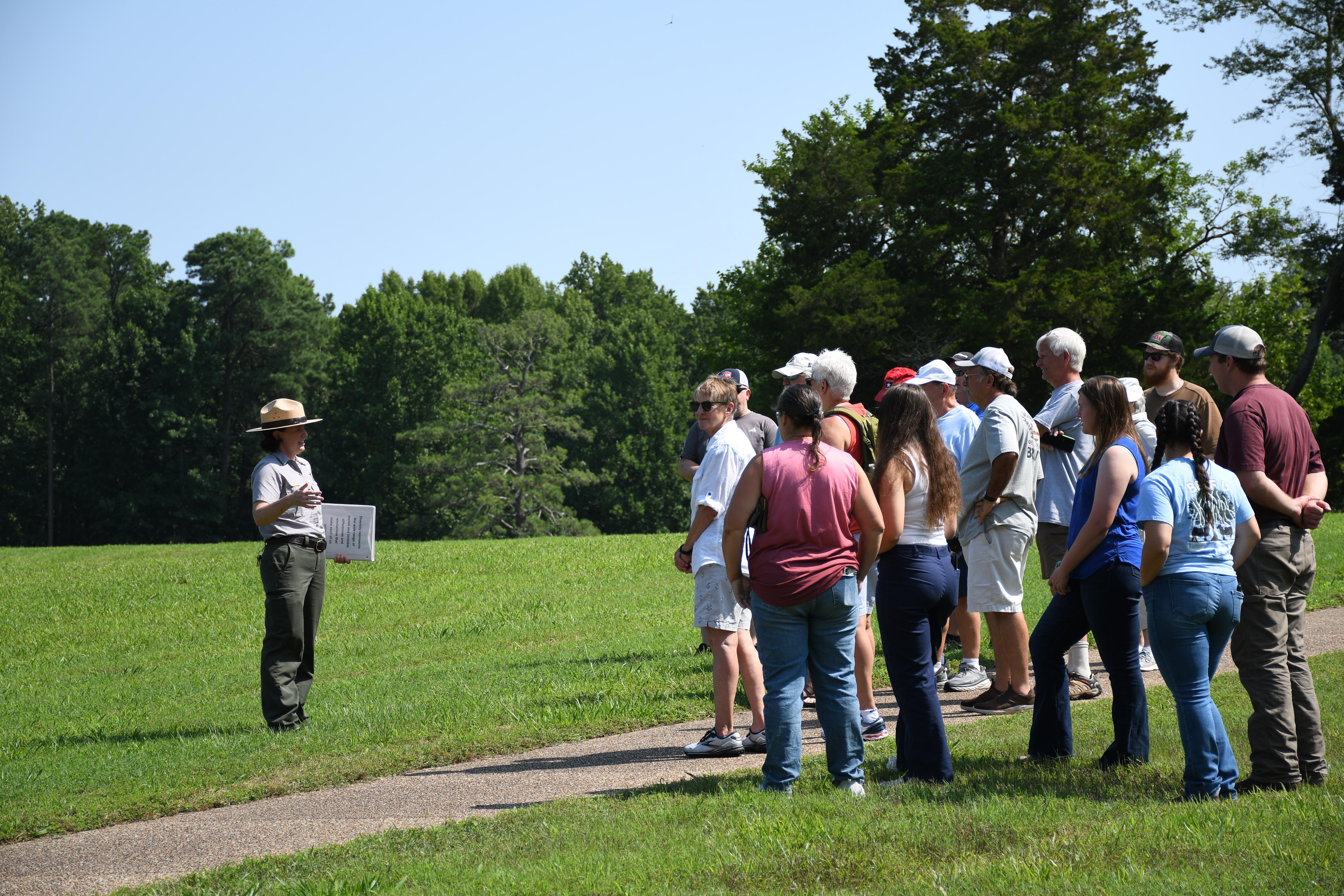 A female Park Ranger talks to a group of visitors on a sunny day,