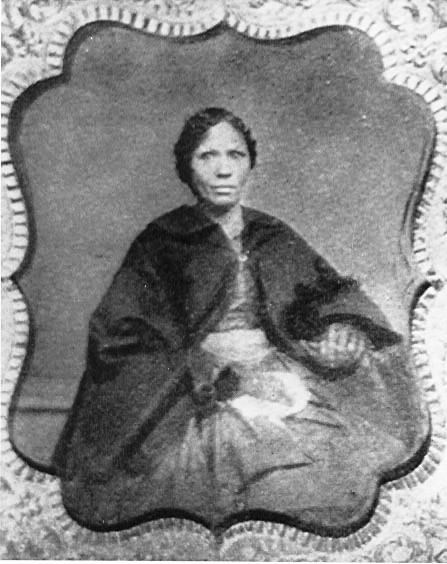 A lady seating wearing a black shawl.