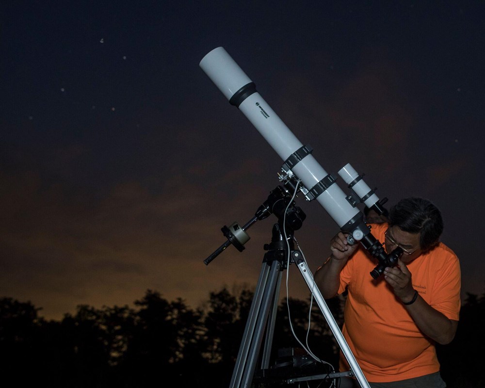 A person looking through a telescope pointed at the night sky.