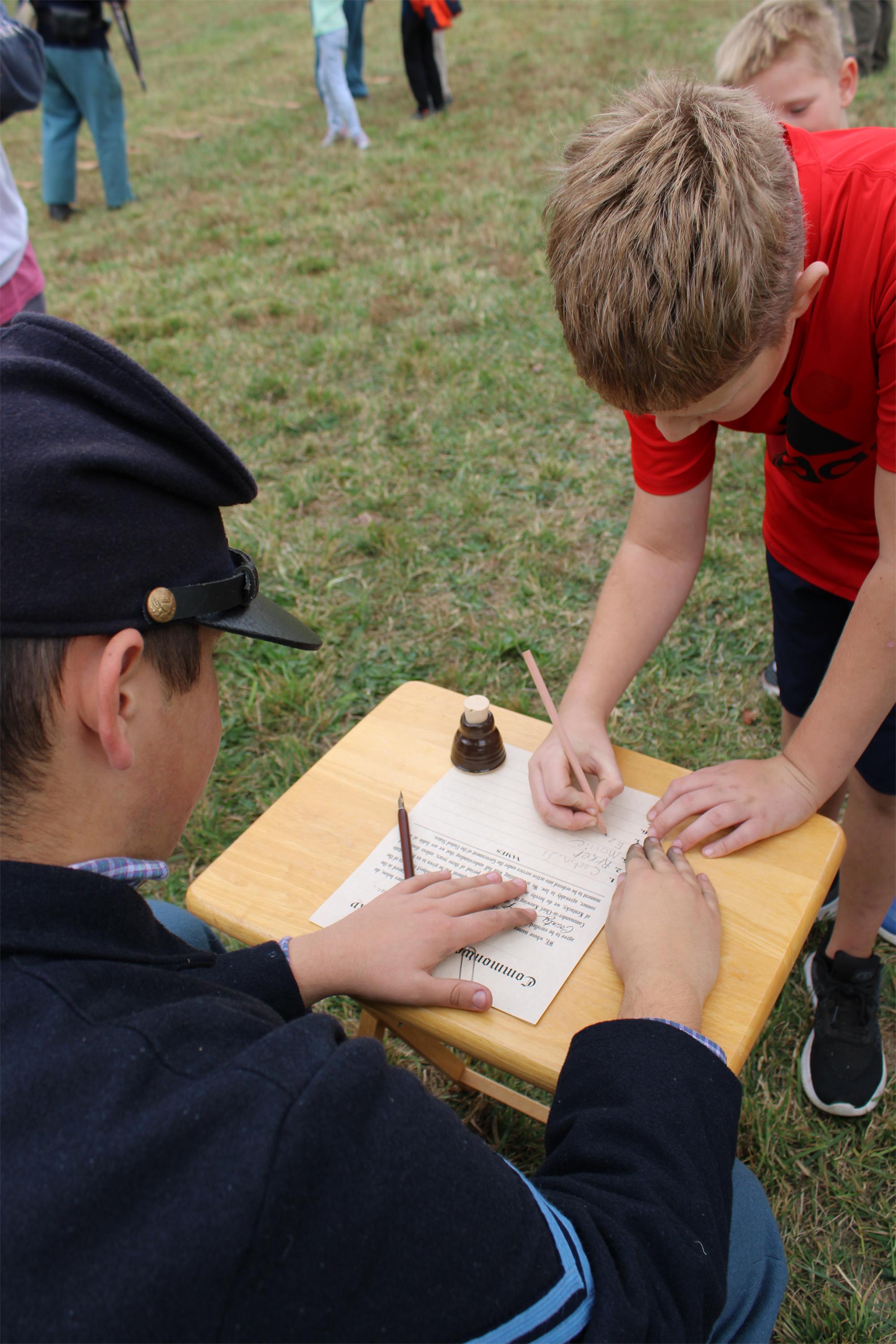 A view over the right should of a Civil War reenactor in blue uniform having a sign a paper.