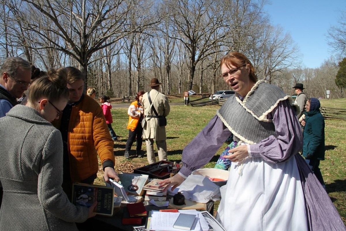woman in 19th century costume talks with visitors