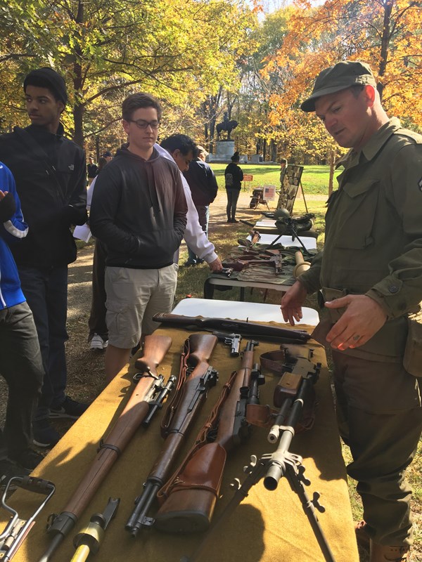 Living history soldier explains display of weapons to visitor