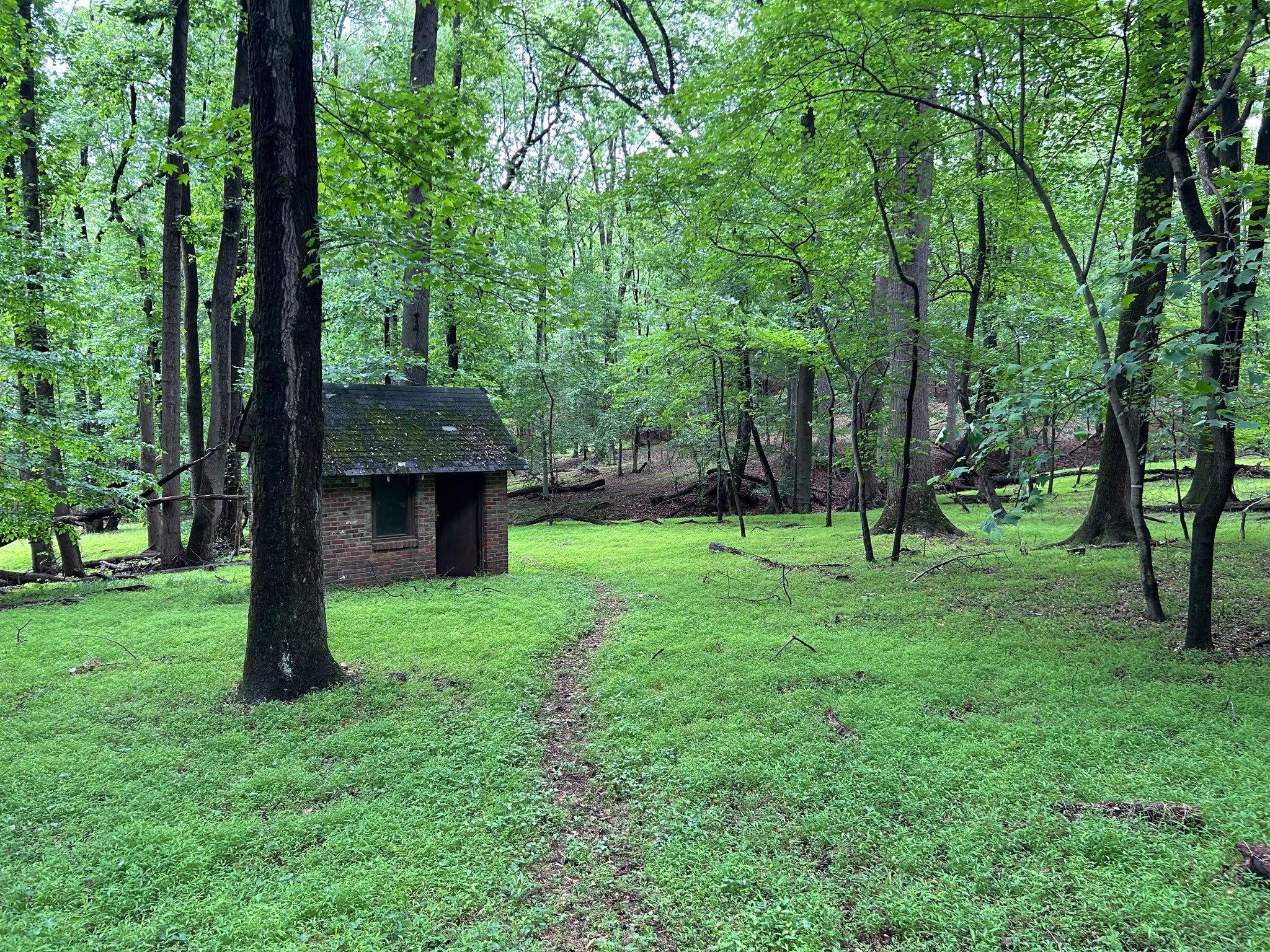 Dirt path through grassland with a brick building