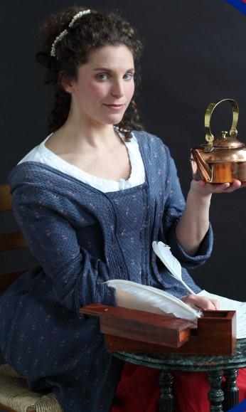 Photograph of woman seated in 1770's garb holding a lantern.