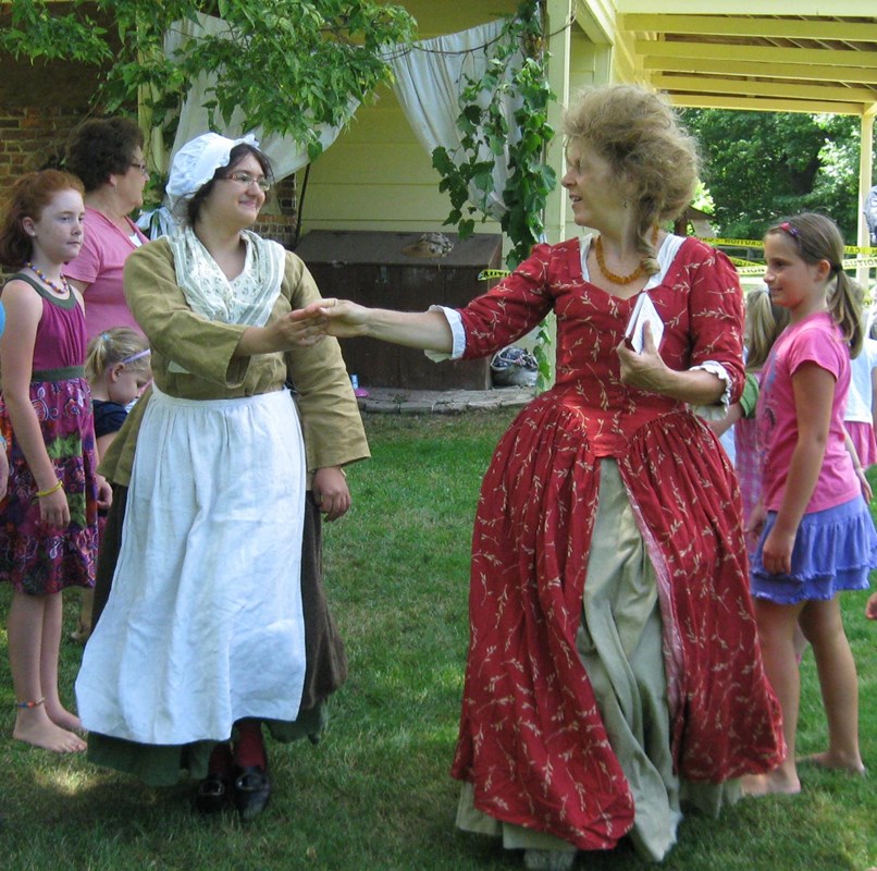 two women in historical clothing demonstrate a dance