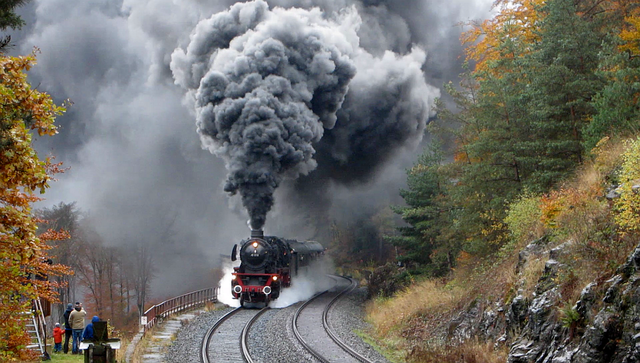 Photograph of a turn-of-the-century steam locomotive bellowing black smoke and steam.