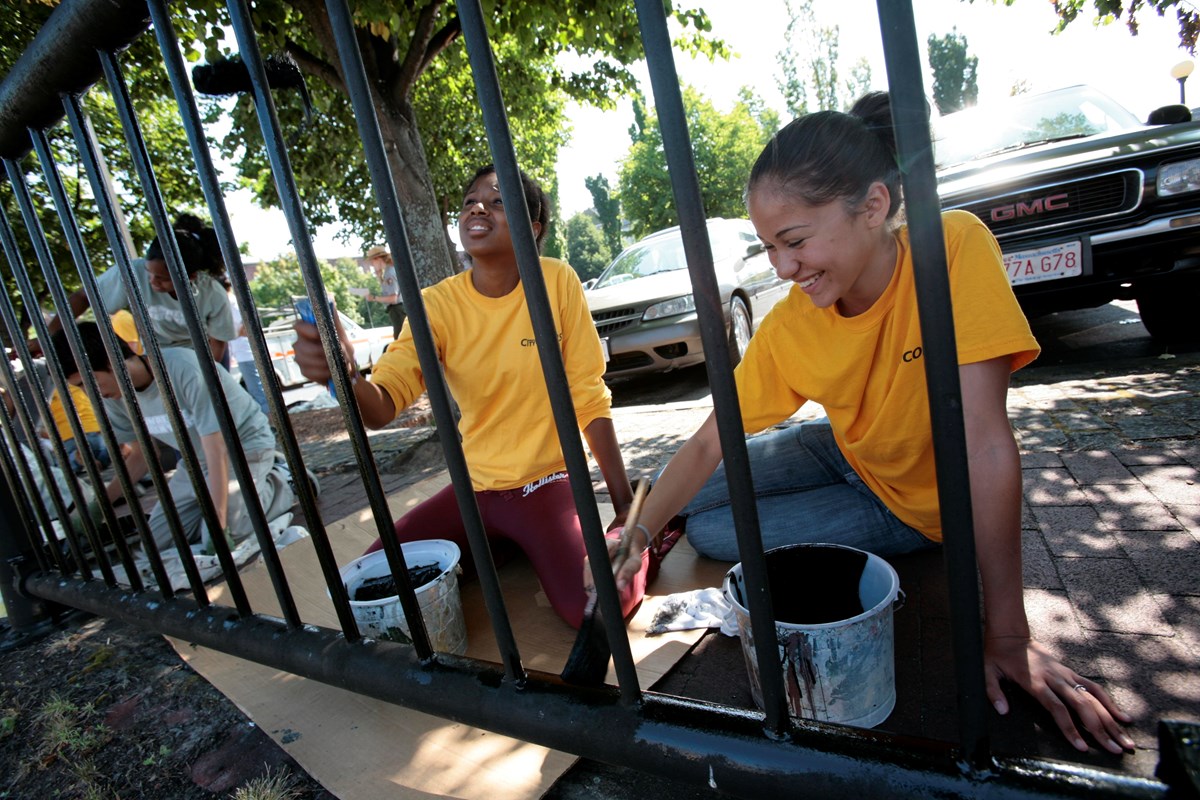Teens work to paint a fence in downtown Lowell